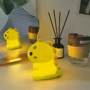 Petite veilleuse dinosaure jaune lumineuse posée sur une table